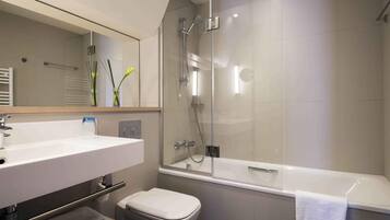 A modern bathroom with a glass-enclosed shower, a white sink, and a toilet.