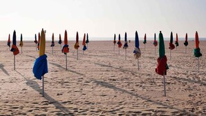 A beach with rows of umbrellas and chairs. - Mercure Deauville Centre (Deauville)
