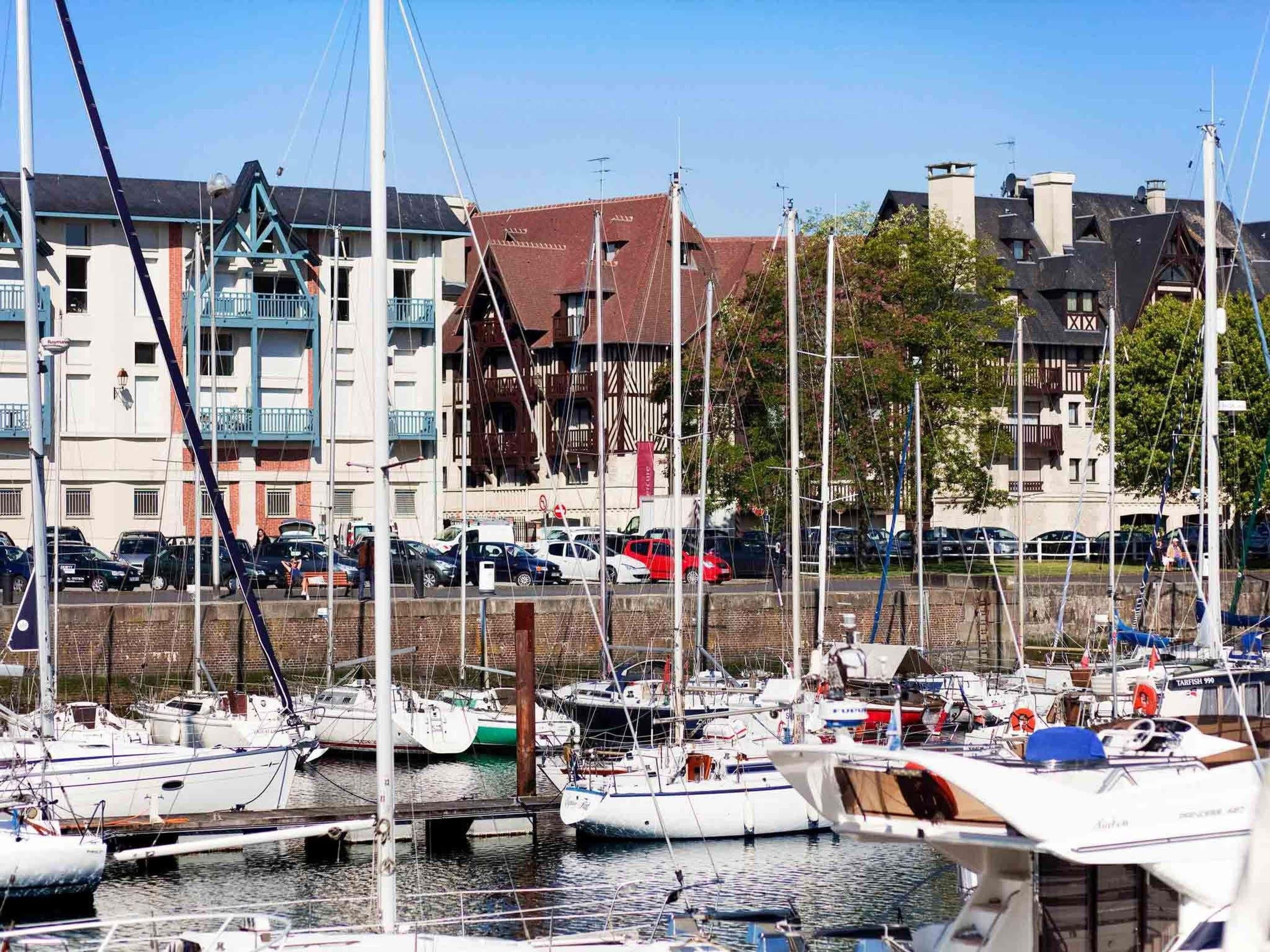 Een jachthaven met aangemeerde boten, een brug en gebouwen op de achtergrond.