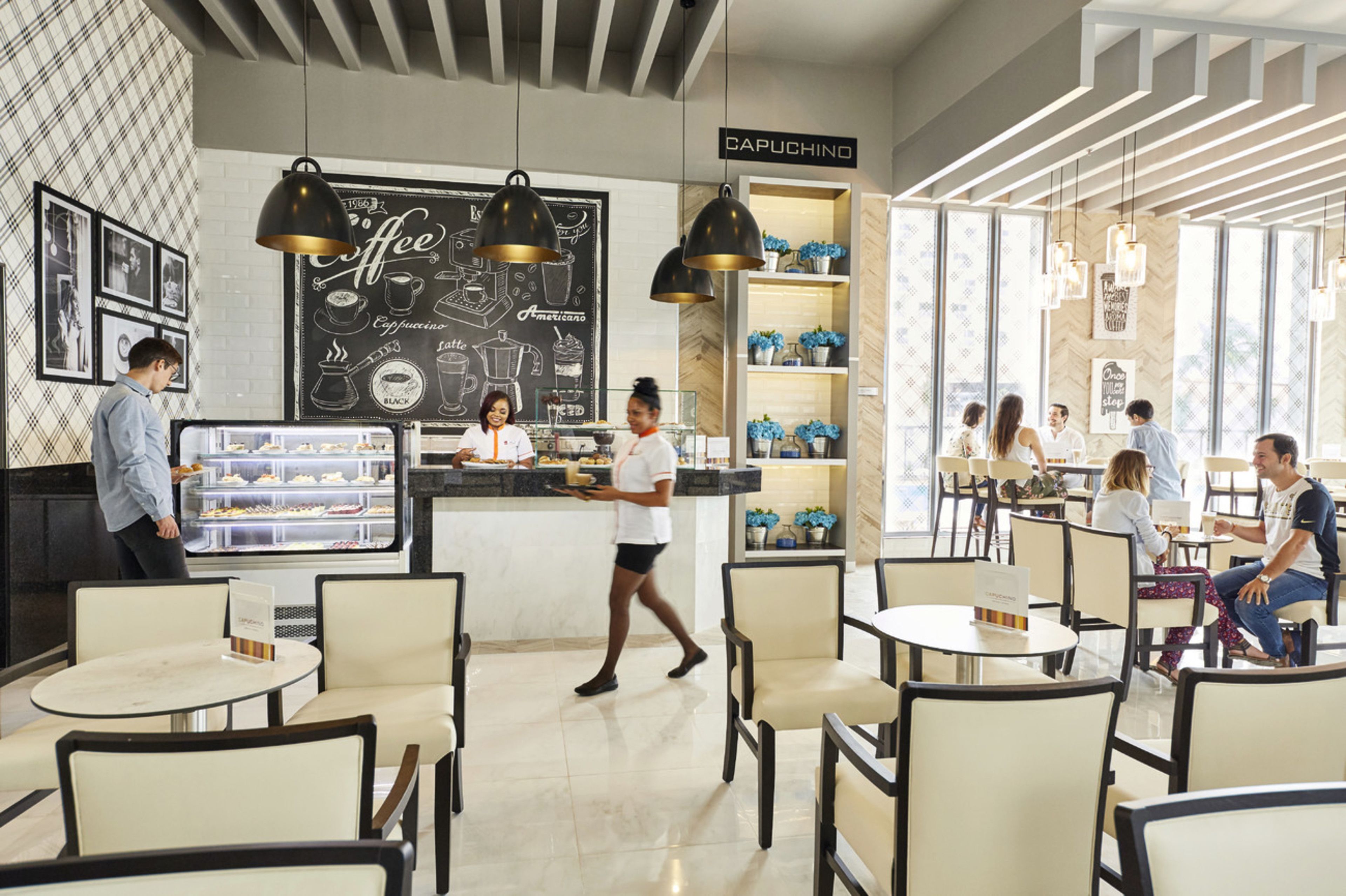 Un café moderne avec un menu écrit à la craie, des espaces pour s’asseoir et un comptoir où un barista prépare les boissons.
