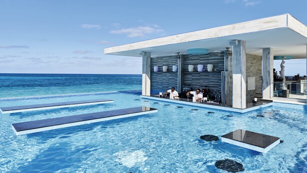 Ein moderner Infinity-Pool mit Barbereich mit Blick auf den Ozean.