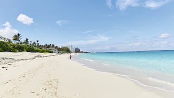 Di pantai, pasir putih, kursi berjemur, dan handuk pantai