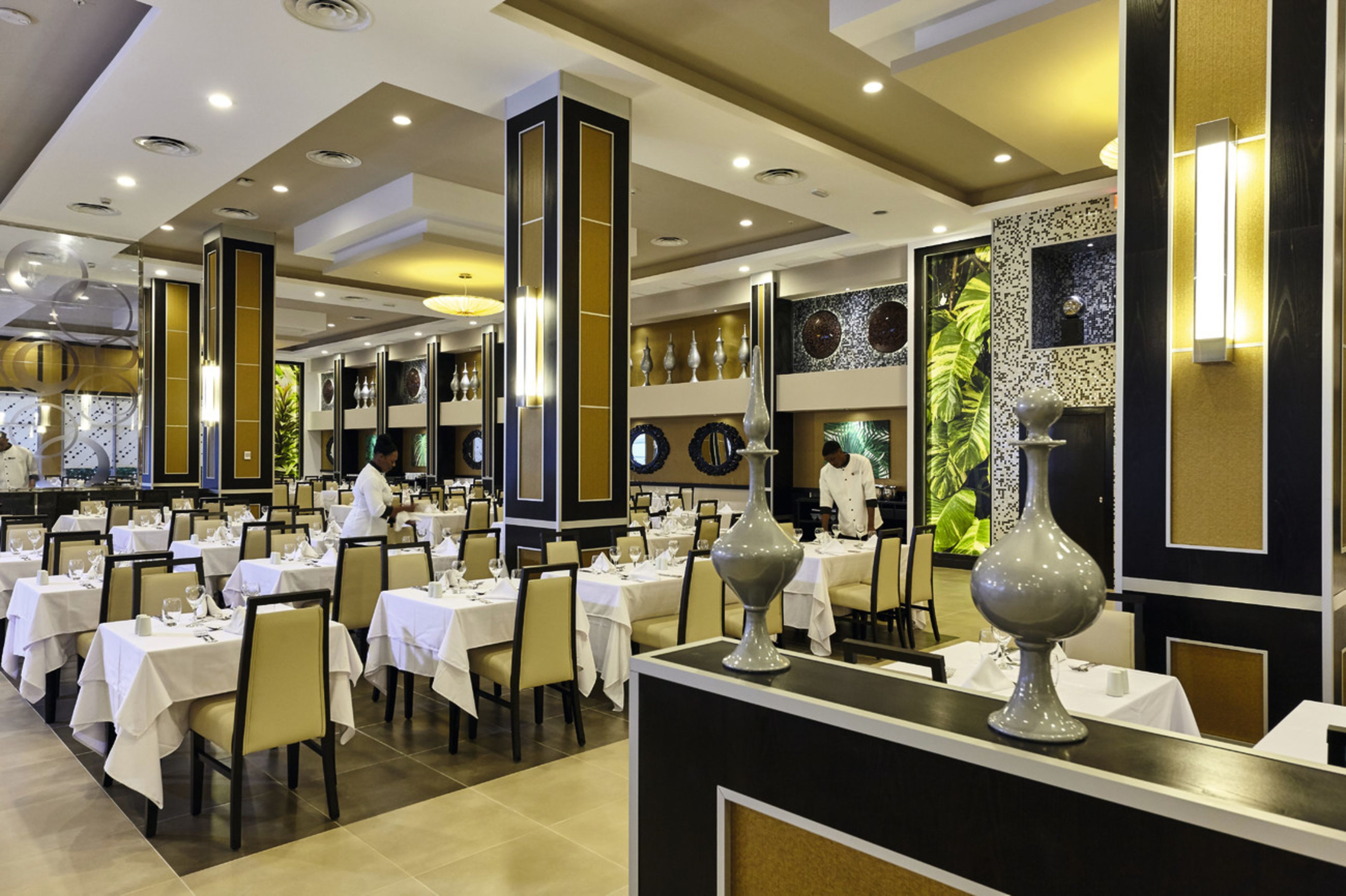 Un vaste espace dédié à la salle à manger, avec plusieurs tables, de hauts plafonds et un décor moderne.