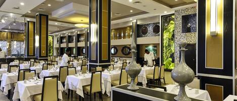 A spacious dining area with multiple tables, high ceilings, and modern decor.