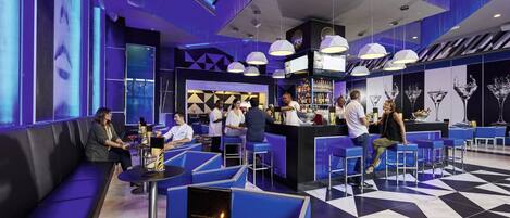 A modern bar area with blue seating, a counter, and a patterned floor.