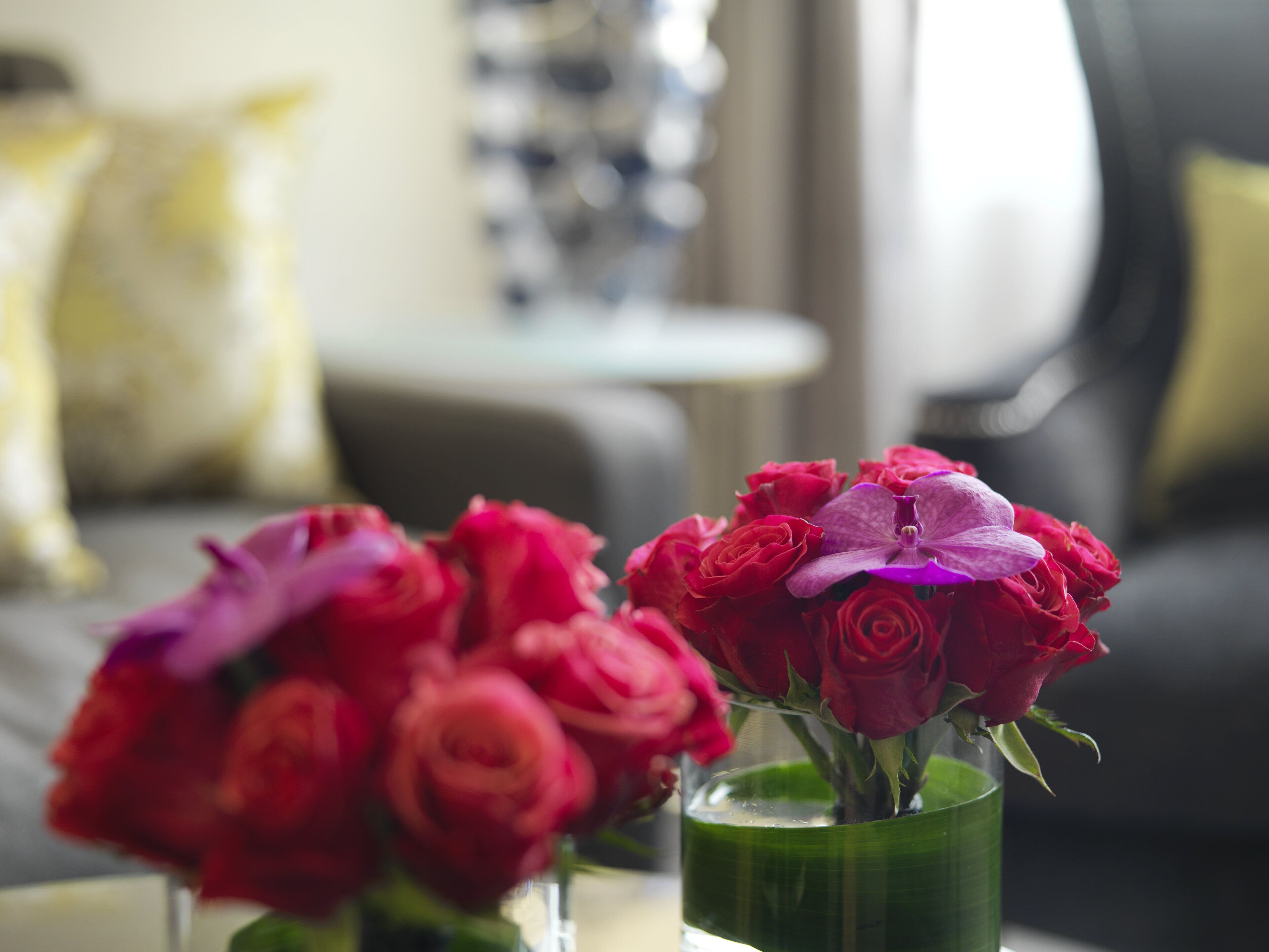 Eine grüne Vase mit roten und rosafarbenen Blumen auf einem Tisch.