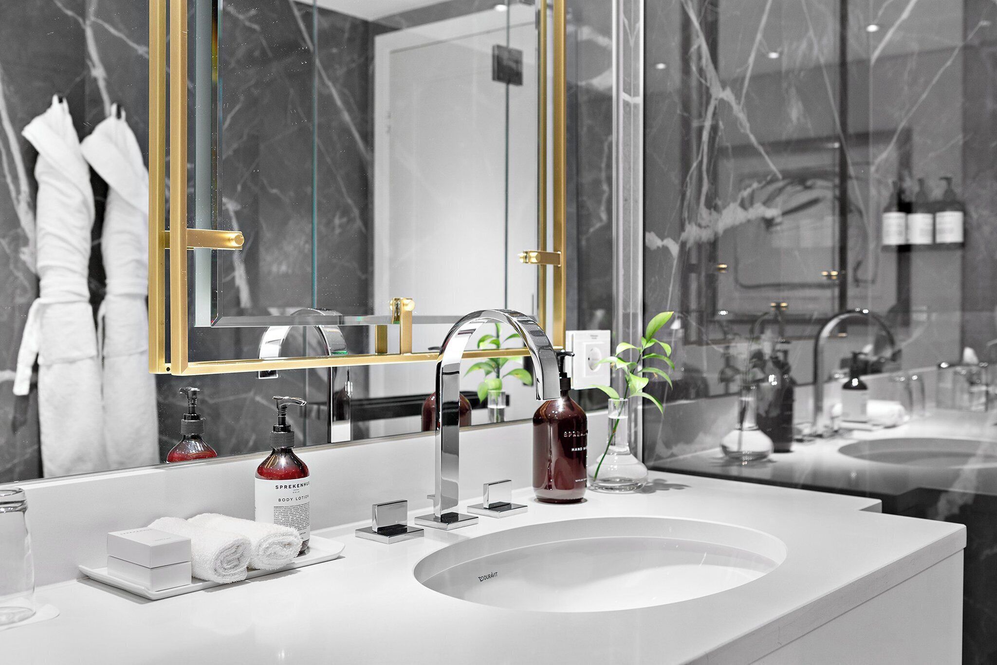 Une salle de bain moderne avec un grand miroir, un lavabo et des articles de toilette.