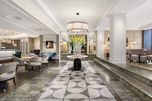 A hotel lobby with a central round table, seating area, and a chandelier. - Hotel Continental (Oslo)