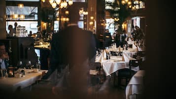 Un restaurante con mesas dispuestas para comer, una zona de bar y vistas a la calle.