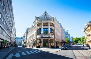 A corner building with a theater cafe, large windows, and a tram line. - Hotel Continental (Oslo)
