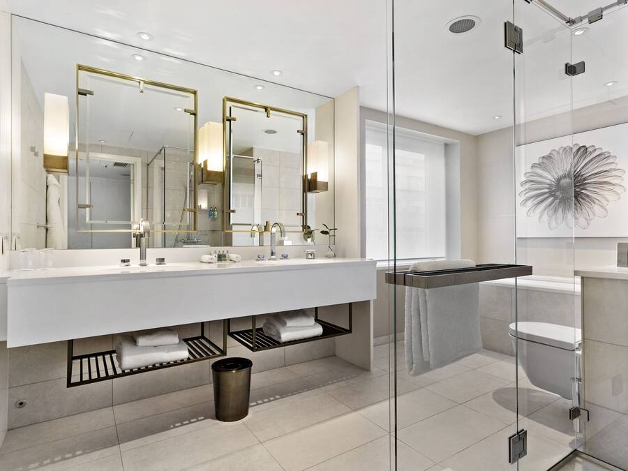 A modern bathroom with a large mirror, dual sinks, and a glass shower enclosure.