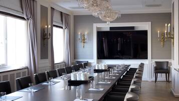 A conference room with a long table, chairs, and a large screen.