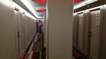 A hotel corridor with a striped carpet, white walls, and doors numbered 105.