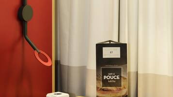 A white device on a wooden surface, a black box with text, and a red wall with a black object.