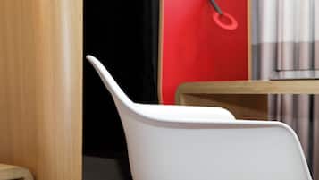 A white chair in a room with a wooden table and a red wall.
