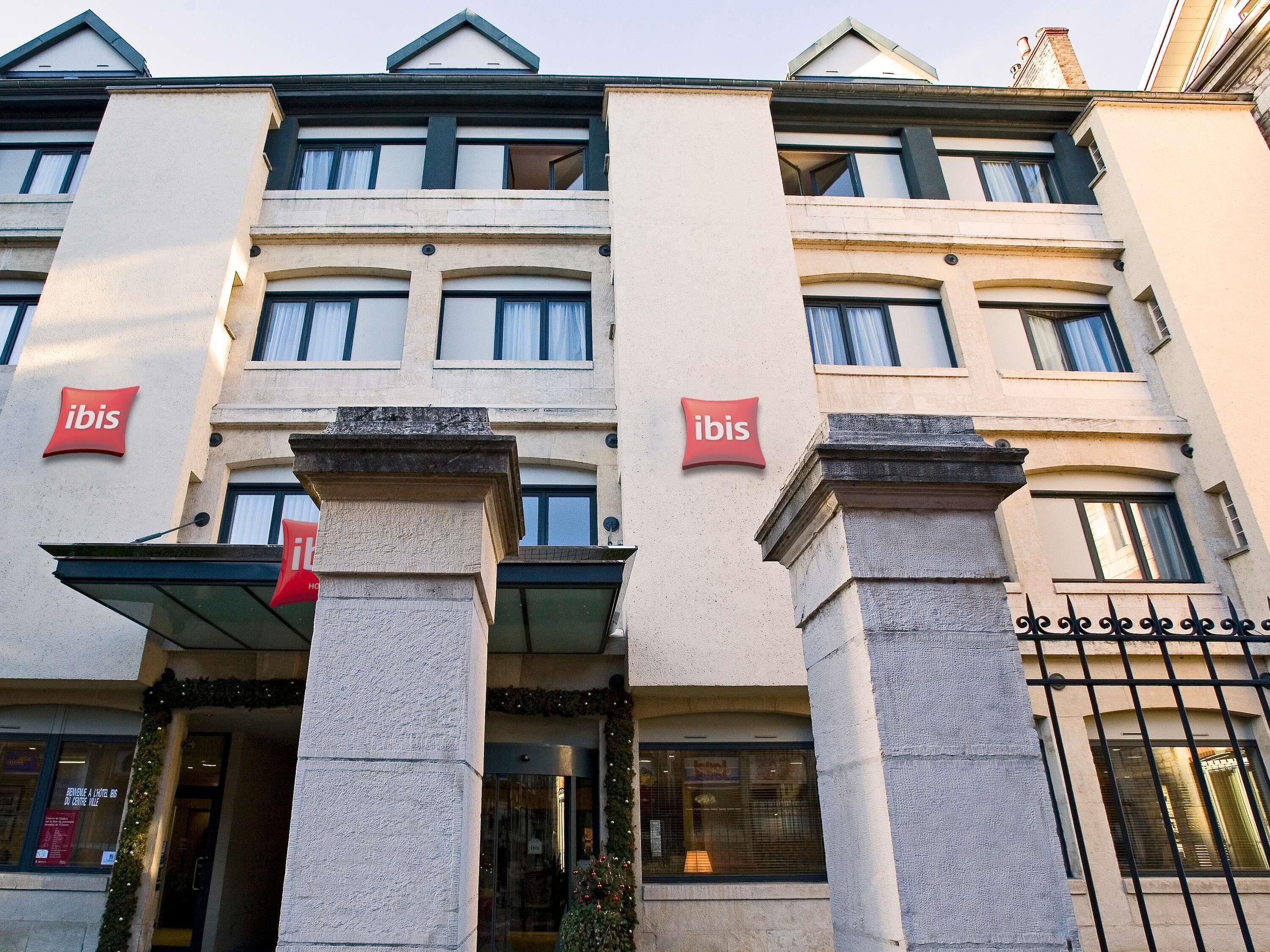 Un hotel con letrero 'ibis', estilo arquitectónico clásico y entrada con portón.