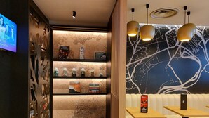 A modern hotel lobby with a wooden reception desk, seating area, and a wall with a tree branch design. - ibis Besancon Centre Ville (Besancon)