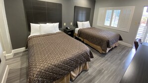 A hotel room with two beds, dark headboards, and a window with blinds. - Budget Inn of Hayward (Hayward)