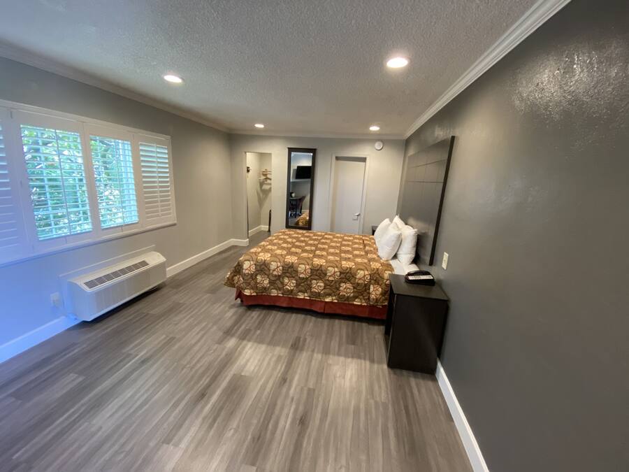 Um quarto com uma cama, aquecedor, janela com persianas e porta.