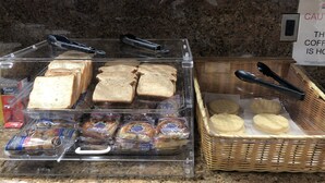 A breakfast display with bread, pastries, and tongs. - Budget Inn of Hayward (Hayward)