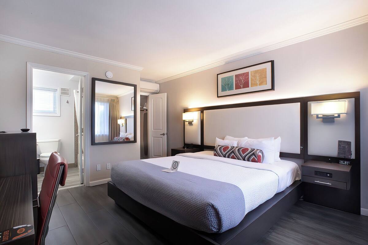 A modern hotel room with a large bed, bedside tables, a desk, and a chair.