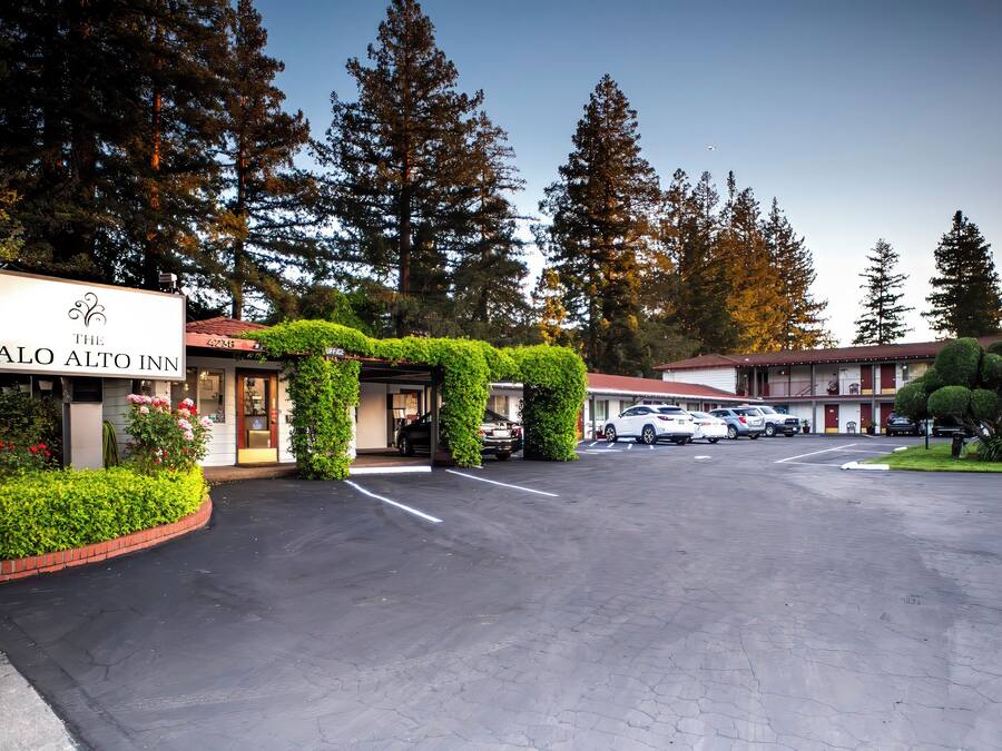 Un parcheggio con un edificio con la scritta 'The Palo Alto Inn' e un cartello con un motivo decorativo.