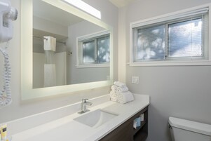 Un baño con lavamanos blanco, un espejo grande, toallero y retrete.