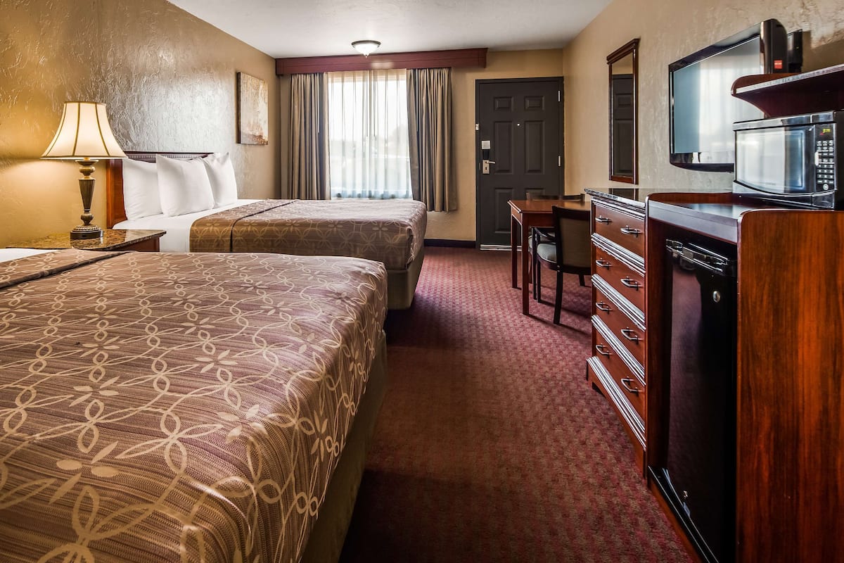 A hotel room with two beds, a desk, a television, and a minibar.