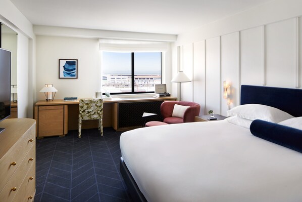 Une chambre d’hôtel avec un grand lit, un bureau avec une chaise, une fenêtre donnant sur un beau paysage et un téléviseur.