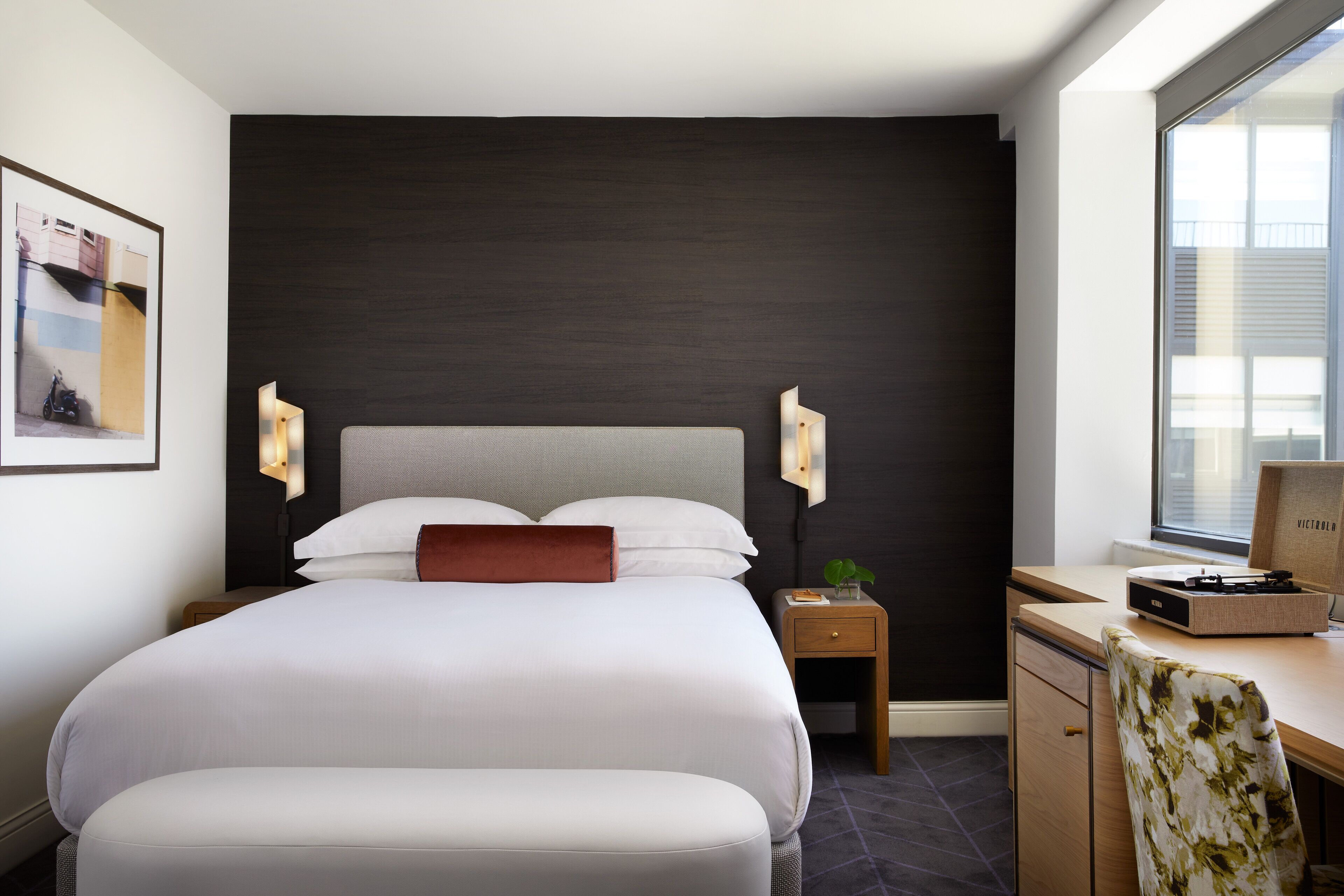 Ein modernes Hotelzimmer mit einem großen Bett, einem Schreibtisch und einem Fenster.