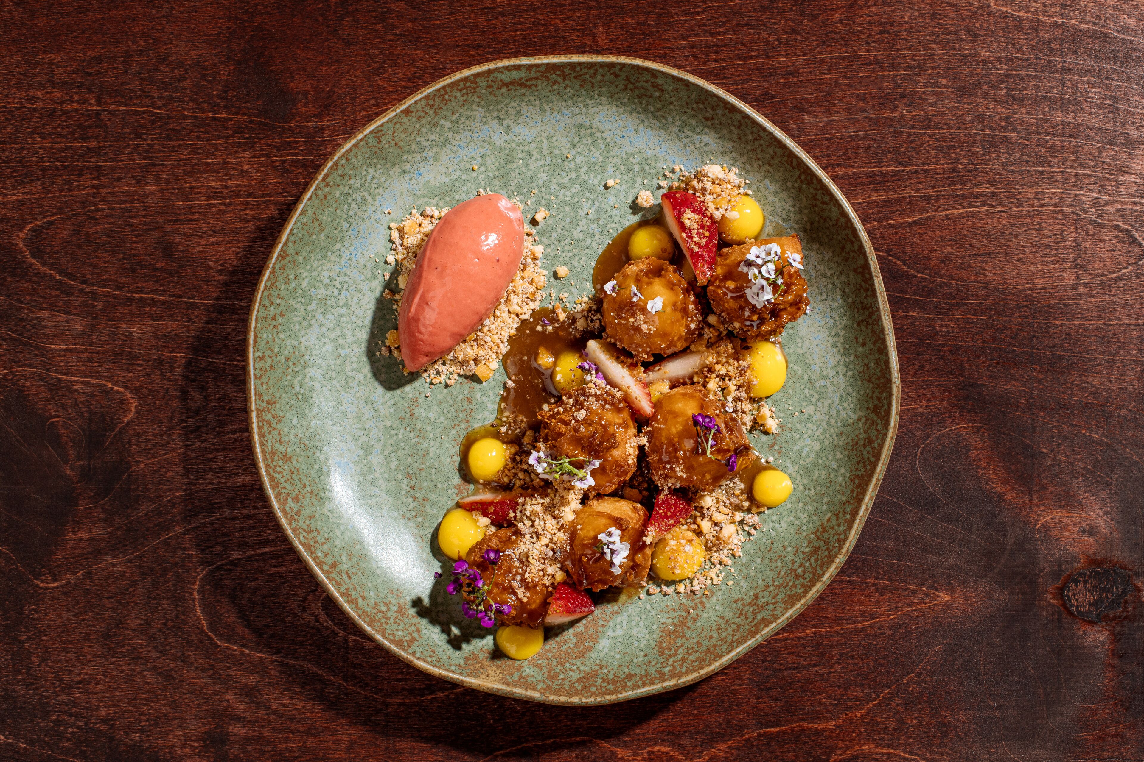 Une assiette à dessert garnie de diverses douceurs et surmontée d’une boule de glace, le tout présenté sur une assiette en céramique rustique.