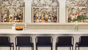 A bar area with three arched mirrors, a variety of bottles, and black chairs. - Kimpton Alton Fisherman's Wharf by IHG (San Francisco)