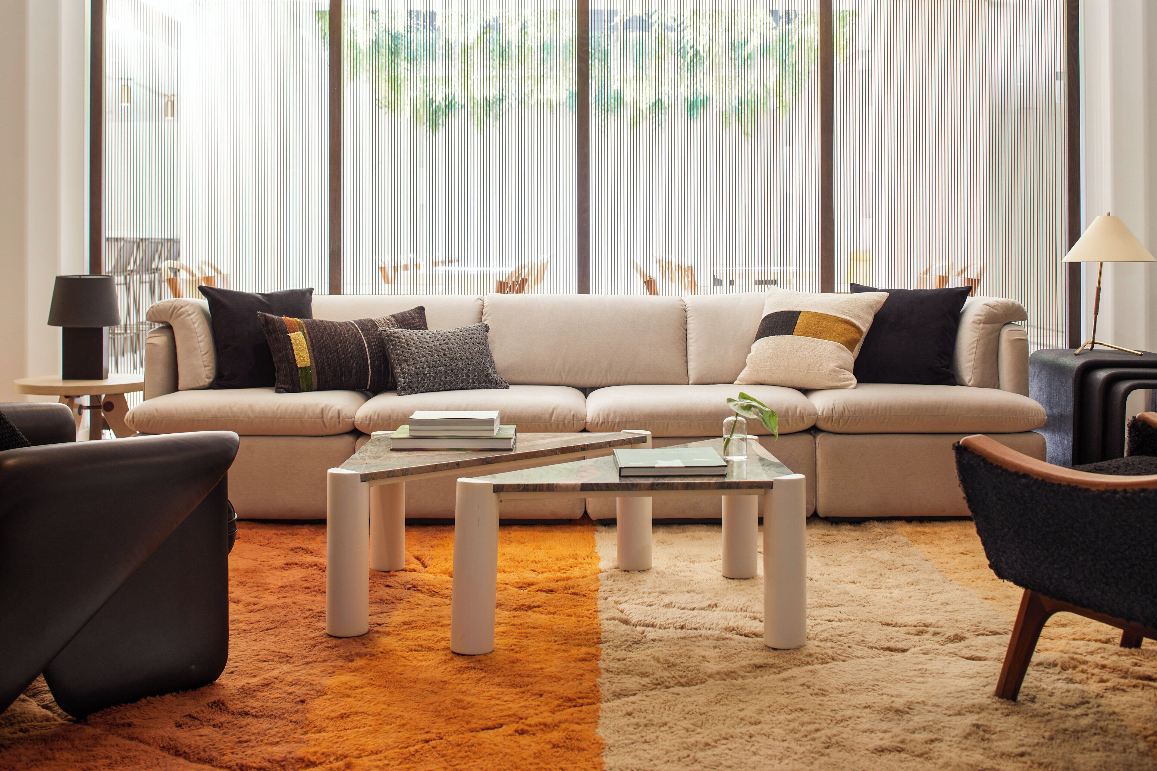 A modern living room with a sectional sofa, two side tables, a coffee table, and a lamp.