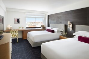 Une chambre d’hôtel avec deux lits, un bureau et une grande fenêtre.