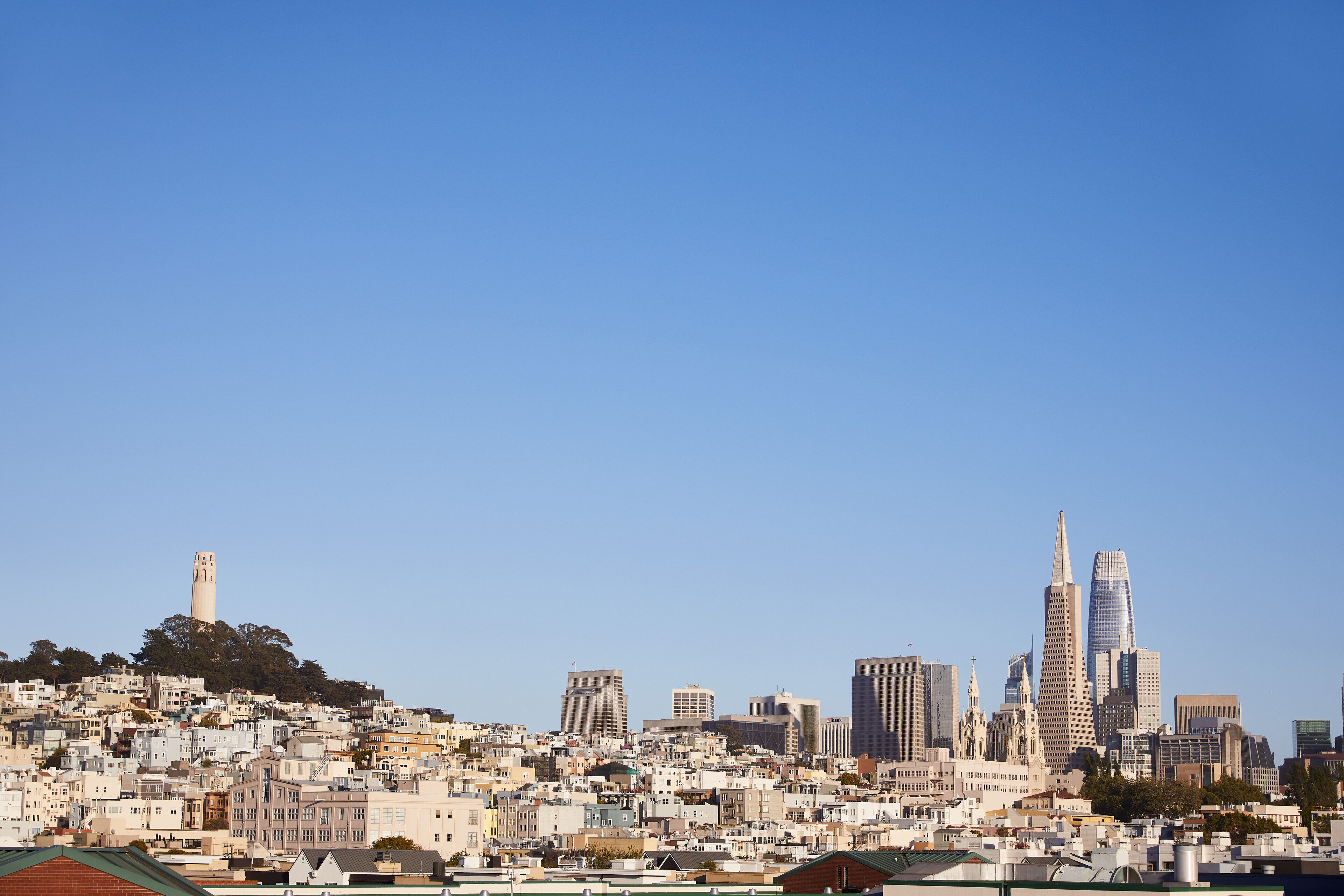 A cityscape with a prominent tower on a hill, a variety of buildings, and a clear blue sky.