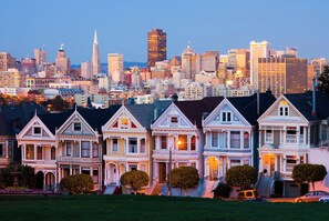 A row of Victorian-style houses with a city skyline in the background. - Kimpton Alton Fisherman's Wharf by IHG (San Francisco)