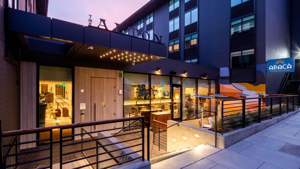 A modern hotel exterior with a glass facade, outdoor seating area, and a staircase leading to the entrance. - Kimpton Alton Fisherman's Wharf by IHG (San Francisco)