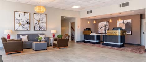 A spacious lobby with a reception desk, seating area, and artwork on the walls.