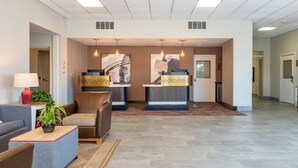A hotel lobby with a reception desk, seating area, and a plant.