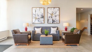 A modern living room with a grey sofa, two armchairs, a coffee table, and two abstract paintings.