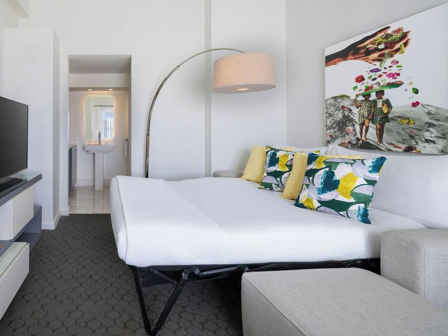 Una camera d'albergo con un letto, una TV, una scrivania e una lampada.