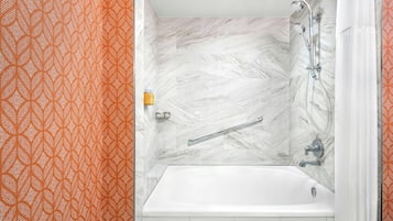 Un baño con una bañera blanca, una ducha con cabezal de ducha manual y un perchero para toallas.