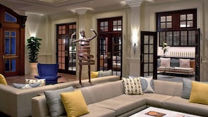 A modern lobby with a large beige sectional sofa, a blue armchair, and a coffee table with magazines. - Hotel Colonnade Coral Gables, Autograph Collection (Coral Gables)