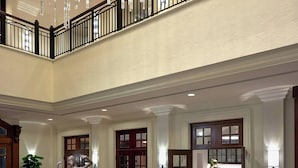 A spacious living area with a large sectional sofa, a coffee table, and a blue armchair. There is a staircase with a railing leading to an upper level. - Hotel Colonnade Coral Gables, Autograph Collection (Coral Gables)