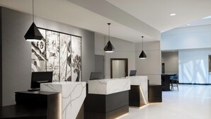 A modern reception area with marble counters, black pendant lighting, and a large abstract artwork on the wall.