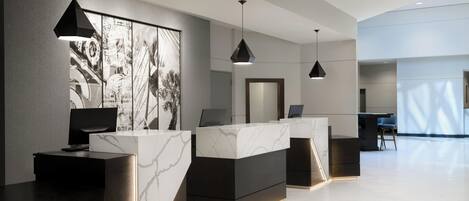 A modern reception area with marble counters, black pendant lighting, and a large abstract artwork on the wall.
