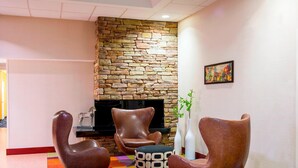 A modern lobby with a stone wall, leather armchairs, a colorful rug, and a painting on the wall. - Fairfield Inn By Marriott Laurel (Laurel)
