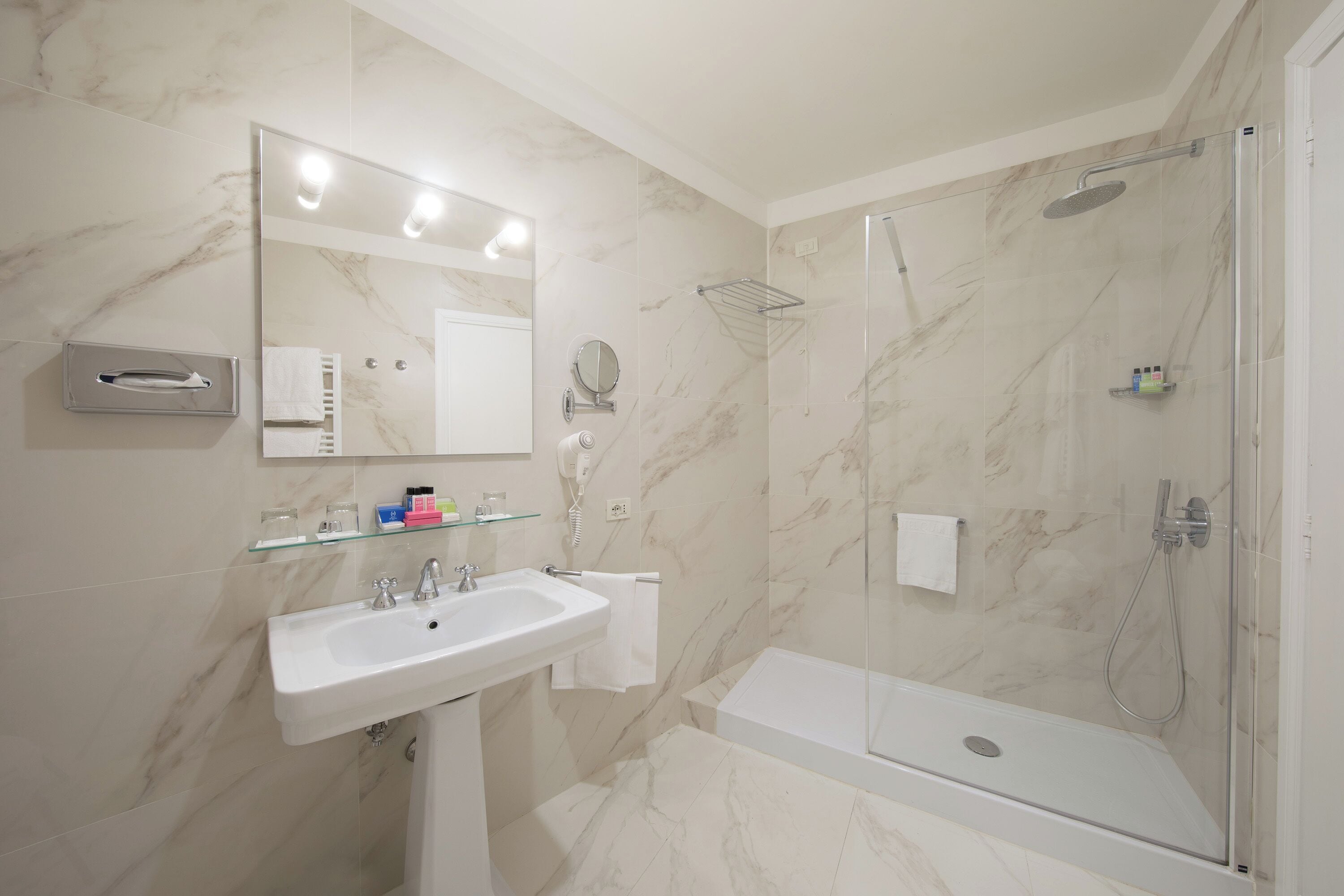 A modern bathroom with a marble sink, a glass-enclosed shower, and a large mirror.