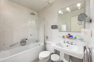 A modern bathroom with a glass-enclosed shower, a white toilet, a sink with a mirror, and toiletries on the countertop.