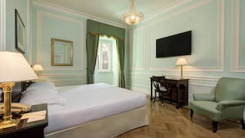 Una habitación de hotel con una cama grande, un escritorio con silla, una televisión y una araña.